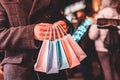 Man holding colorful shopping bags on the dark city background Royalty Free Stock Photo