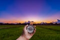 A man holding compass on hand at field and sunset for navigation Royalty Free Stock Photo