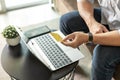 Man holding credit card with laptop and mobile phone sitting on sofa at home Royalty Free Stock Photo