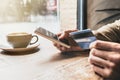 Man holding credit card and using smart phone in a cafe. Online shopping concept Royalty Free Stock Photo