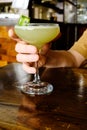 man holding a cucumber gimlet in a stemmed glass