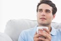 Man holding a cup of coffee sat on the couch Royalty Free Stock Photo