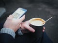 Man holding a cup of coffee and using a smart phone Royalty Free Stock Photo