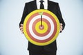 Man holding a dart board with a direct hit on target Royalty Free Stock Photo