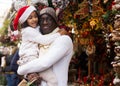 Man holding daughter, looking around at Christmas fair Royalty Free Stock Photo