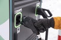 man holding DC charging connector in hand, electric vehicle Combined Charging System CCS2 quick-charge station, alternative energy