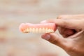 A man is holding dentures in his hands. Removable dentures flexible. False teeth