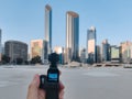 A man holding the DJI OSMO Pocket, an action small camera with a gimbal - vlog shooting in the city | Abu Dhabi skyline and landma