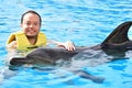 Man holding dolphin in pool Royalty Free Stock Photo