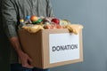 Man holding donation box with food on gray background
