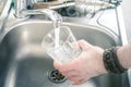 Man Holding A Drinking Glass Over Kitchen Sink Filling It With Water Pouring From Faucet Royalty Free Stock Photo