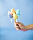 Man holding Easter eggs on a stick on a blue background Royalty Free Stock Photo