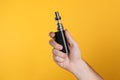 Man holding electronic cigarette on yellow background, closeup Royalty Free Stock Photo