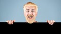 Man holding empty black blank board. Man holding blank paper board studio portrait. Young man shows a sheet of paper in Royalty Free Stock Photo