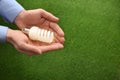 Man holding energy saving bulb for lamp over green grass, closeup. Royalty Free Stock Photo