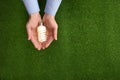 Man holding energy saving bulb for lamp over green grass, top view. Royalty Free Stock Photo