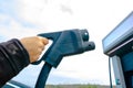 Man holding a EV charger. EV Charger station on the background.