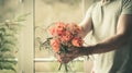 Man holding a festive orange bouquet in his hand against the background of a window and a natural background