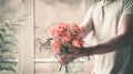 man holding festive orange bouquet in his hand against the background of a window and a natural background