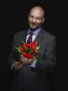 Man holding fresh red tulip bouquet in his hands. Model is bald with grey beard, wearing classic grey suit. Handsome male with
