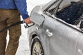 Man holding fuel nozzle, filling gas tank of car covered with snow in winter Royalty Free Stock Photo