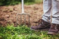 Man is holding a gardening fork, sticking in the ground