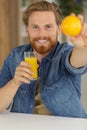 man holding glass juice and fresh orange