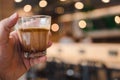 Man holding a glass of Mocha dirty coffee, pouring a mocha shot into a cup with frozen milk
