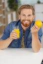 man holding glass orange juice and fresh orange