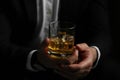 Man holding glass of whiskey with ice cubes on black background, closeup Royalty Free Stock Photo