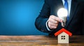 Man is holding a glowing light bulb over the house. Smart home concept. Provision of housing with electricity and communications.