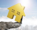 Man holding golden house on cliff edge Royalty Free Stock Photo