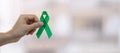 Man holding green Ribbon for supporting people living and illness. Liver, Gallbladders bile duct, kidney Cancer and Lymphoma