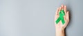 Man holding green Ribbon for supporting people living and illness. Liver, Gallbladders bile duct, kidney Cancer and Lymphoma
