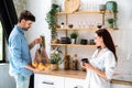 Man holding groceries in mesh bag standing near woman in modern kitchen Royalty Free Stock Photo