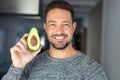 Man holding halved avocado with toothy smile