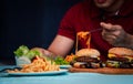 Man holding hamburger on the wooden plate after delivery man delivers foods at home. Concept of binge eating disorder BED and Royalty Free Stock Photo