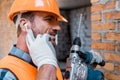 Man holding hammer drill and touching earphones Royalty Free Stock Photo