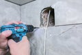 Man is holding hand drill in hands. Worker installing the wall bathroom fan vent. Restoration process