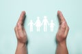 Man holding hands around cutout paper silhouette of family on light blue background, top view. Insurance concept Royalty Free Stock Photo