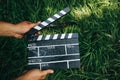 Man is holding in hands black clapperboard with film lying on the grass outdoors. Directing and of amateur cinema movie. Creative