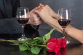 Man holding hands of girl on restaurant table with two red wine glasses and red roses flower Royalty Free Stock Photo