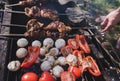 Man holding in hands grilled vegetables, chicken and pork meat on the open fire. Onions, mushrooms, tomatoes and red pepper on the Royalty Free Stock Photo