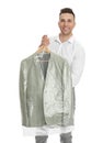 Man holding hanger with jacket in plastic bag on background. Dry-cleaning service Royalty Free Stock Photo