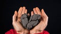 A man holding a heart shaped piece of coal in his hands, AI