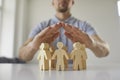 Man holding his hands above wooden human figures as metaphor for safety and protection Royalty Free Stock Photo