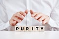 A man holding his hands over the wooden cubes with the word purity
