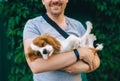 Man holding his King Charles spaniel puppy outside on green background