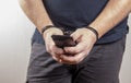 A man holding his phone in handcuffs on a white background,selective focus.Concept: the slave of technology, the right to one call