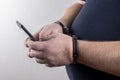 A man holding his phone in handcuffs on a white background,selective focus.Concept: the slave of technology, the right to one call